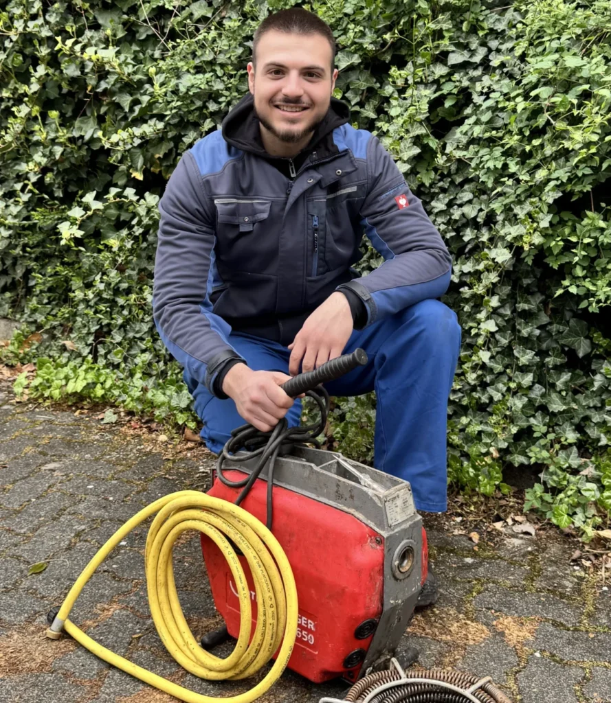 Mitarbeiter reinigt Abfluss mit Rohrreinigungsspirale in Düsseldorf